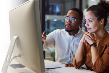 Photo: two people looking at computer screen learning web basics like HTML, CSS, Javascript by attending ONLC Training Centers classes.